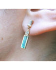 14K gold stud earring with baguette emerald, pear-shaped diamond, and tapered baguette diamond.