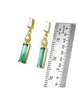 14K gold stud earrings with baguette emeralds, pear-shaped diamond extensions, and tapered baguette diamonds.