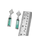 Emerald baguette cut earrings with diamond studs in 14K white gold, next to a ruler for scale.