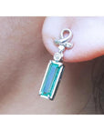 Natural baguette cut emerald earring with a top ribbon-like worn by a person