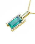 Te left side view of a baguette cut natural emerald pendant in yellow gold.