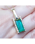 5.15 ct. baguette cut Colombian emerald pendant in 18K yellow gold with diamond accents.