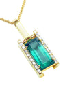 A yellow gold baguette cut emerald pendant with diamond accents topside view.