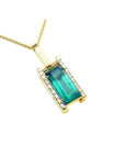 A yellow gold baguette cut emerald pendant with diamond accents topside view.