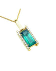 A yellow gold baguette cut emerald pendant with diamond accents topside view.
