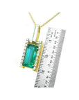 Baguette cut emerald pendant in 18K yellow gold with diamond accents, shown next to a ruler.