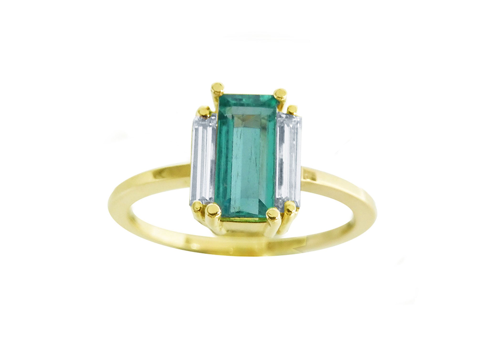 Topside display of a baguette cut emerald and diamond side ring in 18k yellow gold.
