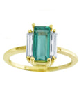 Topside display of a baguette cut emerald and diamond side ring in 18k yellow gold.