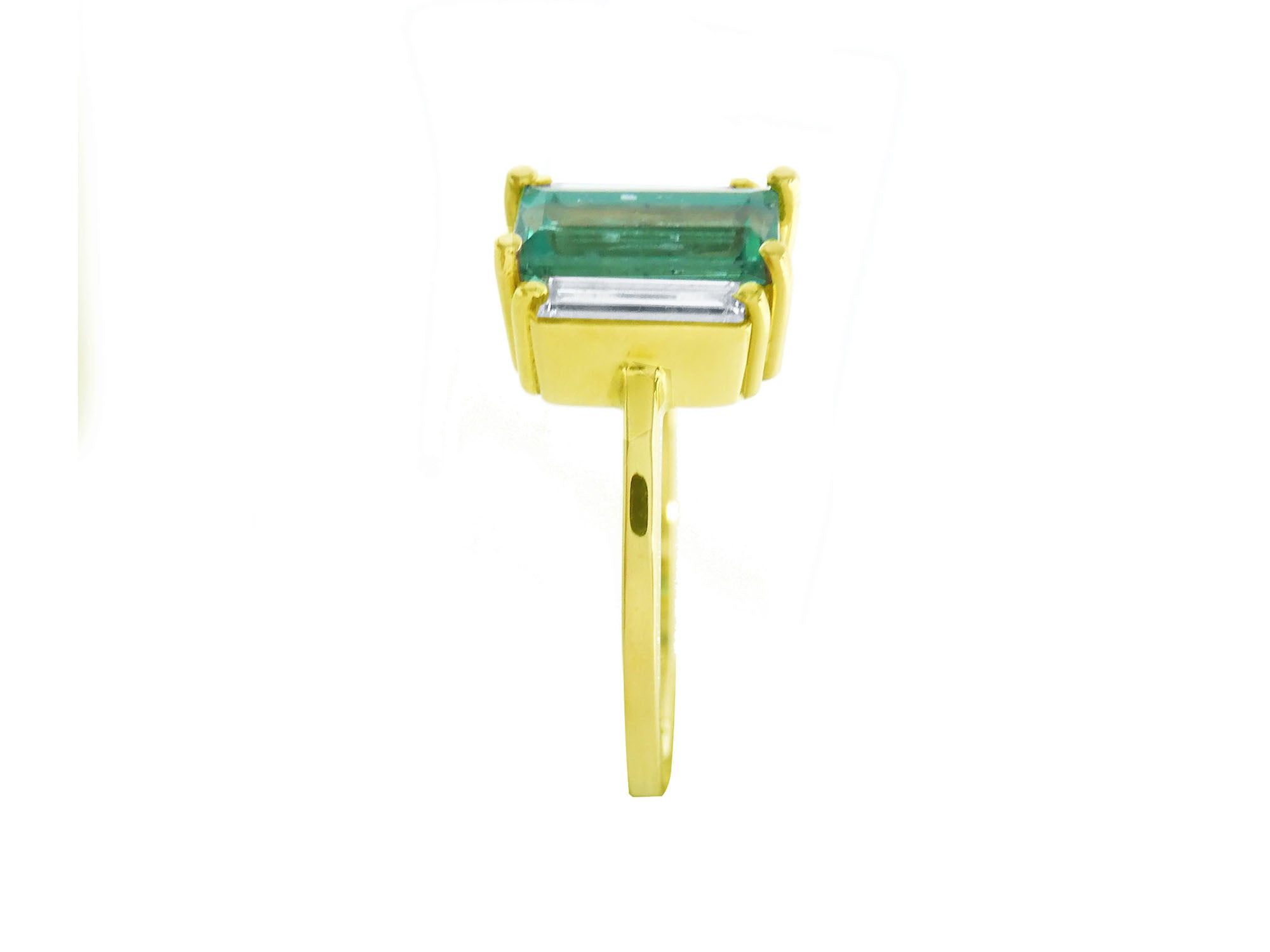 A yellow gold natural emerald and side baguette diamond ring displaying the side profile top and band view.
