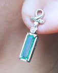 Natural baguette cut emerald earrings with a top ribbon-like worn by a person