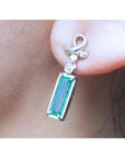 Natural baguette cut emerald earrings with a top ribbon-like worn by a person