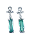 Pair of emerald baguette cut earrings with ribbon-like hooks on a front position full top view.