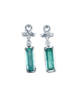 Emerald-cut natural emerald earrings in 14k white gold with diamond ribbon design.