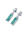 Emerald-cut natural emerald earrings in 14k white gold with ribbon design and accent diamonds.