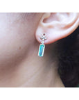 Close-up of an ear wearing a emerald baguette cut and diamond earring in white gold