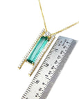 14K yellow gold necklace with a baguette-cut emerald, accent diamonds, and a sliding tube bail.