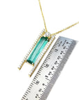 14K yellow gold necklace with a baguette-cut emerald, accent diamonds, and a sliding tube bail.
