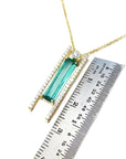 14K yellow gold necklace with a baguette-cut emerald, accent diamonds, and a sliding tube bail.