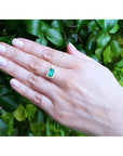 1.14 ct baguette emerald pendant necklace with diamond bail on a woman's hand, 14K yellow gold.
