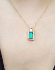 Gold necklace with a natural emerald pendant on a person's neck
