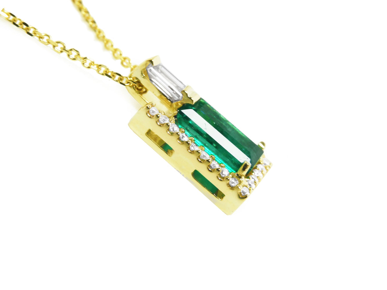 The right-side profile of a yellow gold emerald pendant.