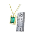 1.14 ct baguette emerald pendant with diamond bail, set in 14K yellow gold, next to a ruler.