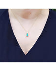 Baguette cut emerald pendant necklace with natural diamonds in 14K yellow gold on a model.