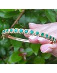 14K gold bangle bracelet with round bluish-green emeralds in square links with rope borders.
