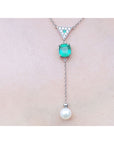Emerald and pearl necklace cushion cut prong set in 14k white gold, dangling from a triangle shaped gold with pave diamonds