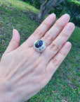 Men's black Ethiopian opal ring with red-orange and blue hues, set in sterling silver on a hand.