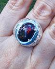 Men's black Ethiopian opal ring with red-orange and blue hues, set in ornate sterling silver.