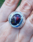 Men's black Ethiopian opal ring with red-orange and blue hues, set in ornate sterling silver.