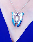 Natural blue agate butterfly pendant necklace with sterling silver chain on a blue top.