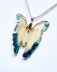 Butterfly-shaped pendant with blue and beige wings on a white background