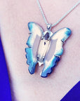 Natural blue agate butterfly pendant necklace with sterling silver frame on a person's neck.