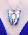 Natural blue agate butterfly pendant with sterling silver frame on a silver chain, worn on a blue top.