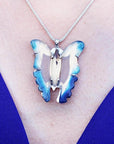 Natural blue agate butterfly pendant with sterling silver frame on a silver chain, worn on a blue top.
