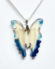 Butterfly-shaped pendant on a chain against a white background