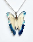 Hand-carved blue agate butterfly pendant with cream body and blue wings, set in sterling silver.