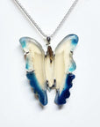 Hand-carved blue agate butterfly pendant with cream body and blue wings, set in sterling silver.