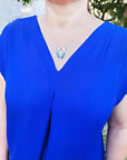 Natural blue agate butterfly pendant necklace with sterling silver frame on a woman's blue top.