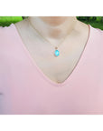 Oval blue-green opal pendant in 14K yellow gold on a woman's neck.