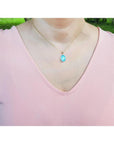 Oval blue-green opal pendant in 14K yellow gold on a woman's neck.