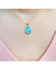 Oval Australian opal pendant with blue-green sparks on a 14K yellow gold chain.