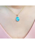 Oval Australian opal pendant with blue-green sparks on a 14K yellow gold chain.