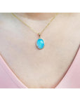 Oval Australian opal pendant with blue-green sparks on a 14K yellow gold chain.