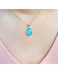 Oval Australian opal pendant with blue-green sparks on a 14K yellow gold chain.