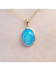 A blue opal pendant necklace on a plain skin background.