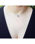 1.01 ct blue sapphire bezel set on a 14K gold cable chain choker necklace worn by a woman.