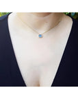 1.01 ct blue sapphire bezel set on a 14K gold cable chain choker necklace worn by a woman.